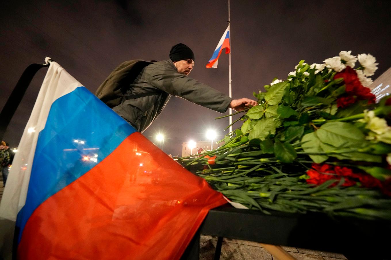 En man lämnar en blomma vid den minnesplats som spontant växt fram utanför konsertlokalen där minst 130 personer miste livet i en attack på fredagskvällen. Foto: Dmitri Lovetsky/AP/TT