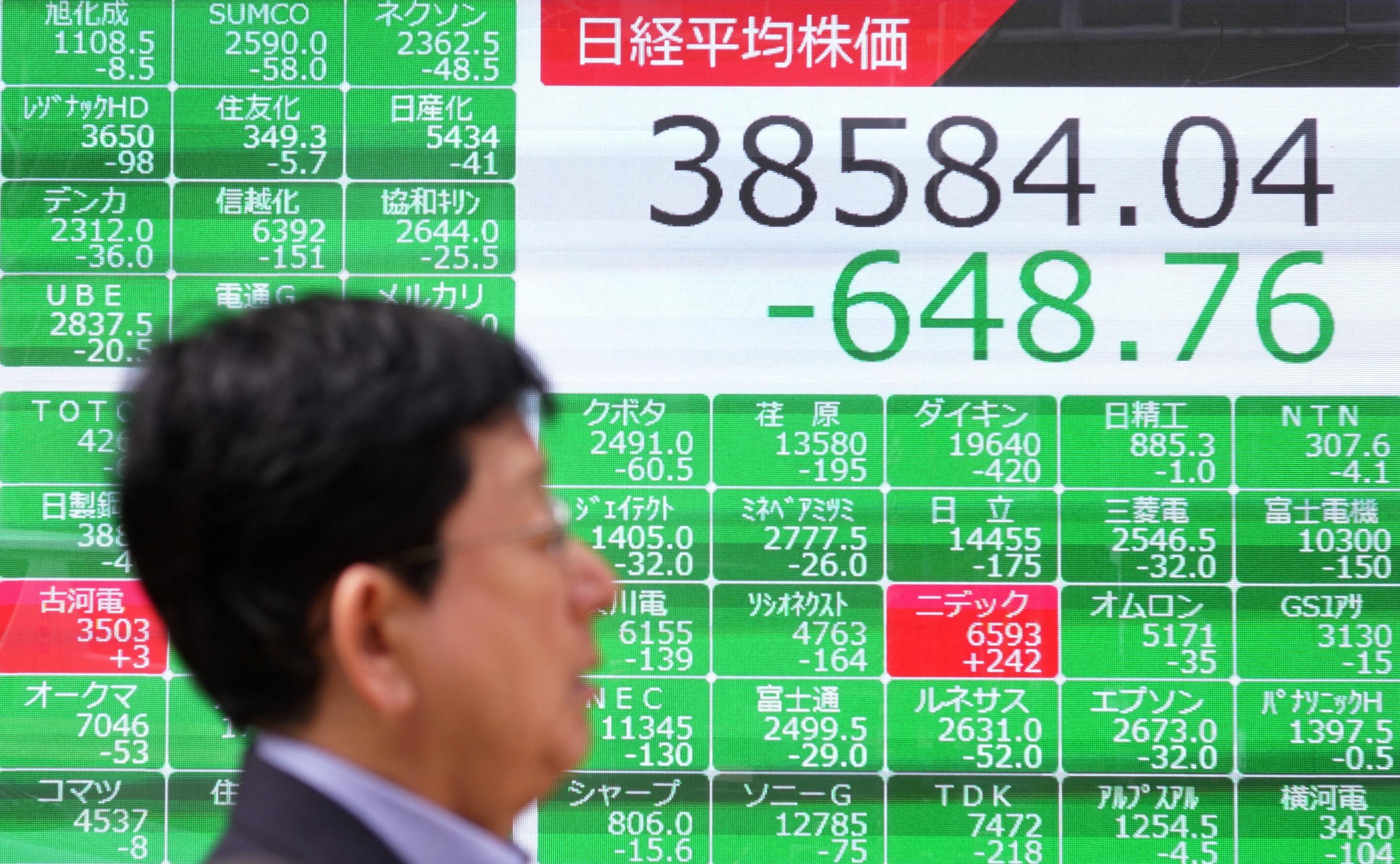 En man går förbi en elektronisk tavla som visar aktiekursen för Nikkei-indexet på Tokyobörsen i Tokyo den 16 april. Foto: Kazuhiro Nogi/AFP via Getty Images