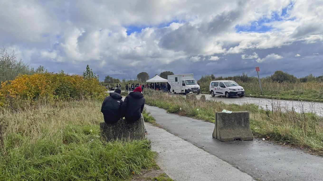 Migranter sitter vid en plats där Röda korset delar ut mat i Calais. Foto: Owen Evans