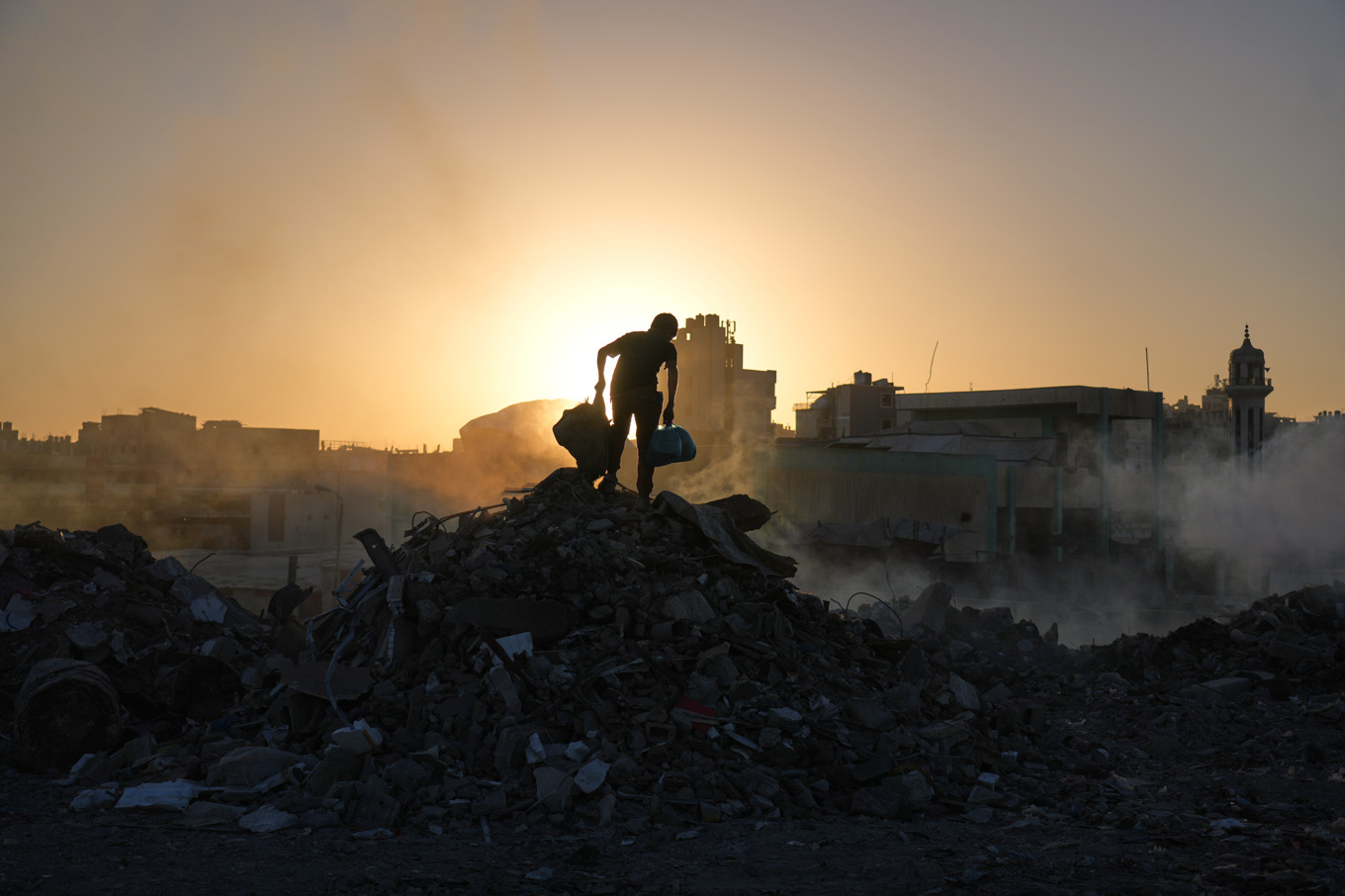 En palestinier letar efter ved i en hög med bråte i Gaza stad under lördagen. Foto: Abdel Kareem HanaAP/TT