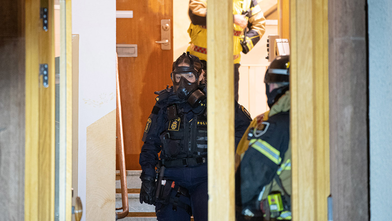 Poliser i skyddsmask arbetar på platsen. Foto: Niklas Luks/TT