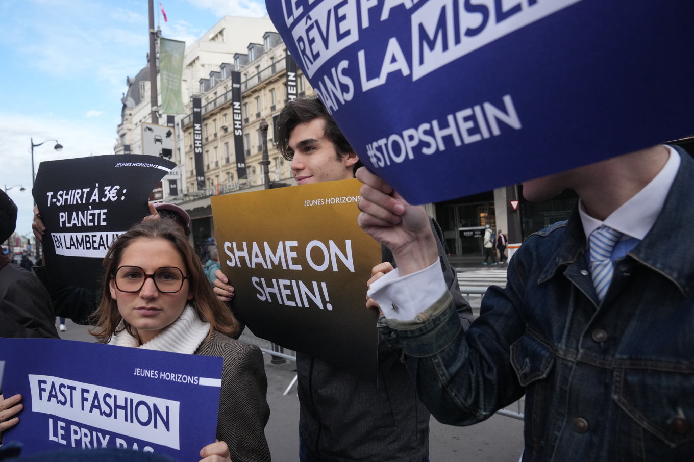 Människor håller upp skyltar i protest utanför Sheins fysiska butik i Paris, som öppnade på onsdagen. Foto: Thibault Camus/AP/TT