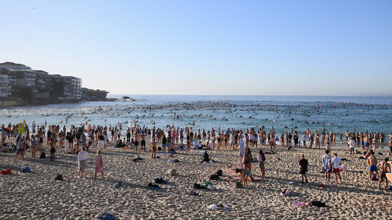 Surfare och simmare hedrar offren efter söndagens skjutning på stranden Bondi Beach. Foto: Steve Markham/AP/TT
