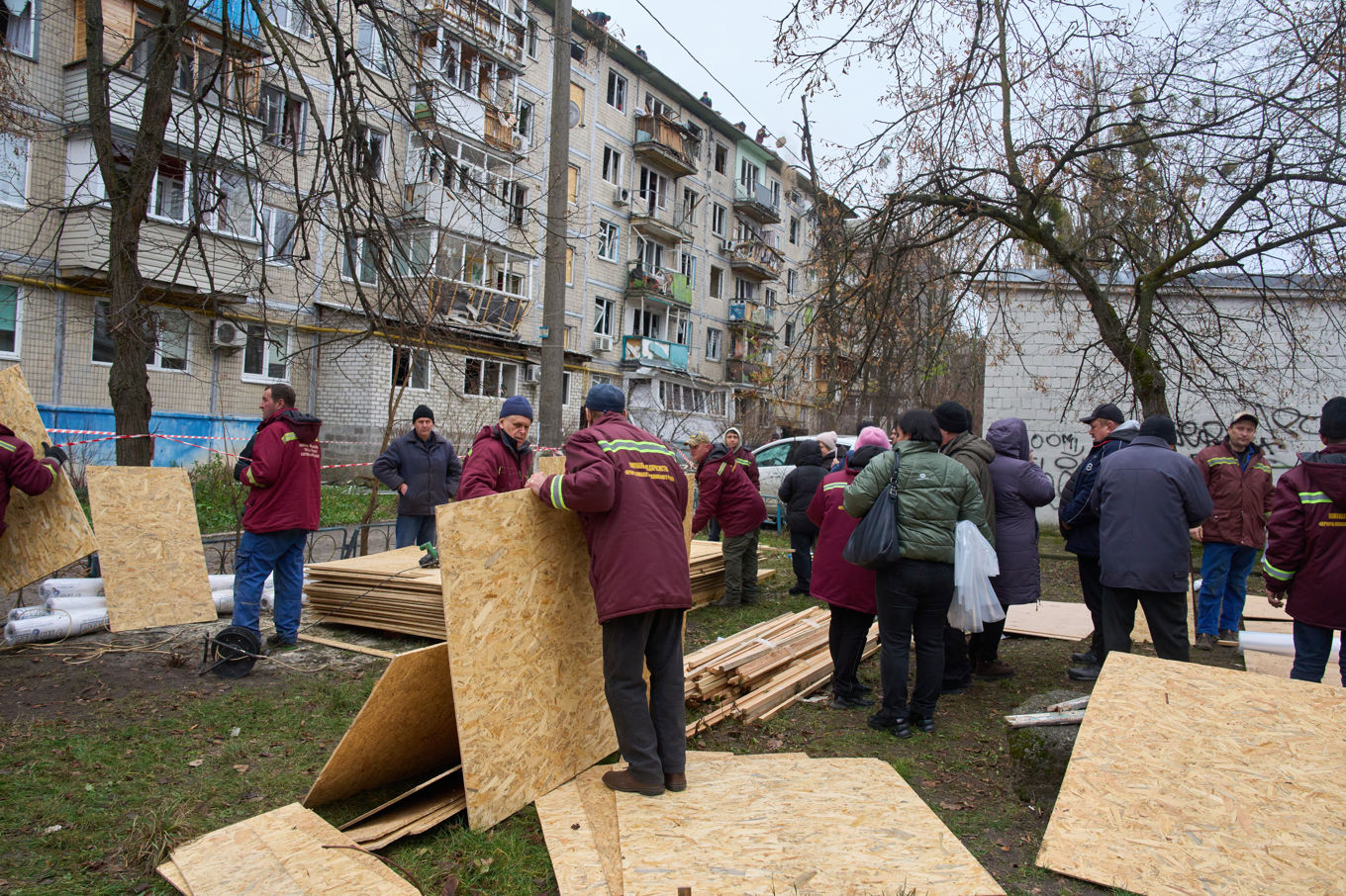 Plywoodskicor delas ut till invånare vars fönster förstörts då ett lägenhetshus träffades av en rysk drönare under en attack i Kiev i tisdags. Foto: Efrem Lukatsky/AP/TT