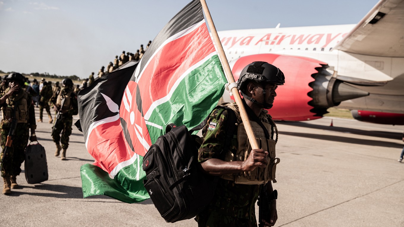 Kenyanska poliser håller upp en kenyansk flagga när de anländer till Toussaint Louverture International Airport i Port-au-Prince i Haiti den 8 december. Foto: Clarens Siffroy/AFP via Getty Images