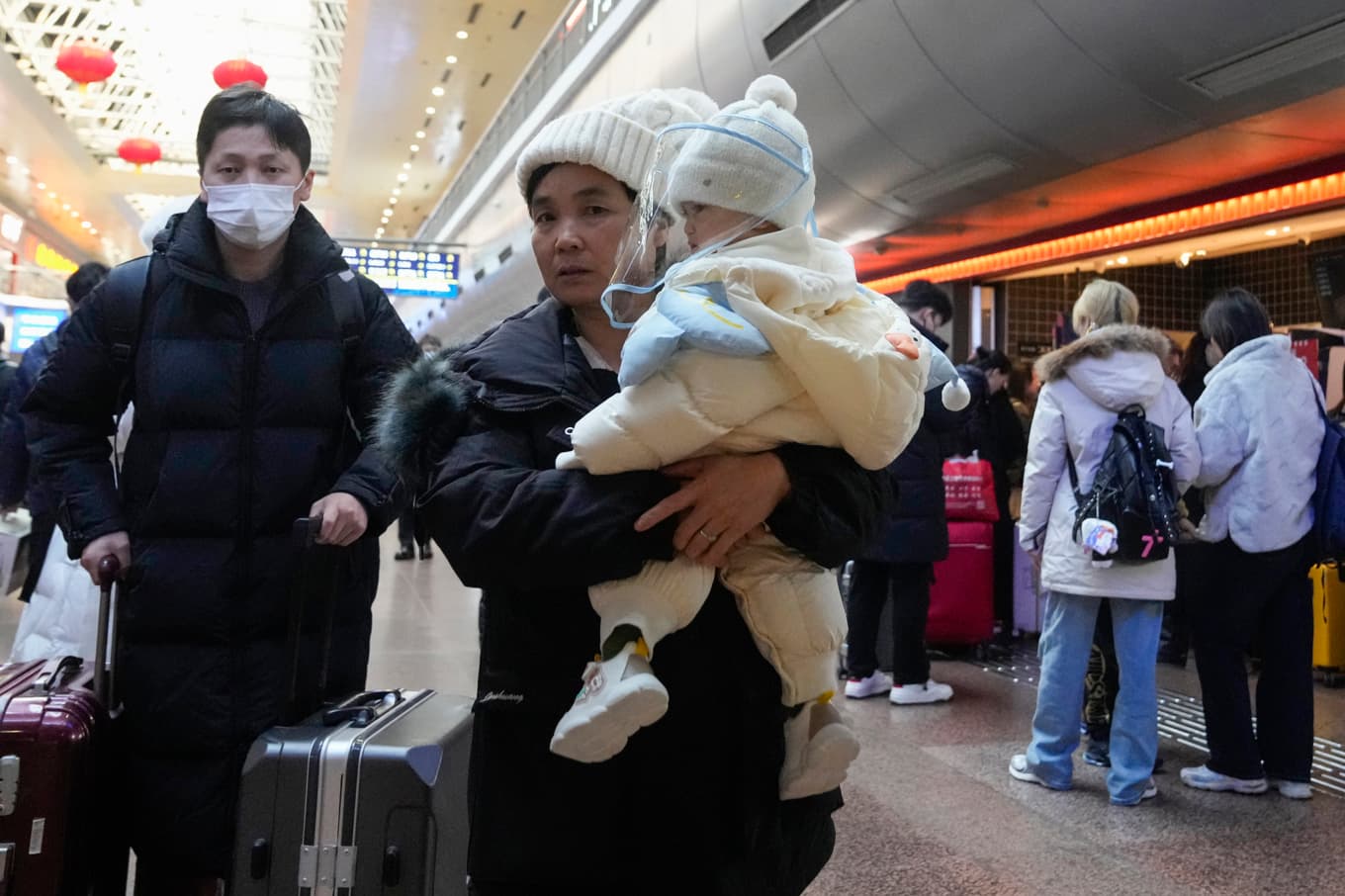 En kinesisk familj på järnvägsstationen i Peking. Arkivbild från i fjol. Foto: Aaron Favila/AP/TT