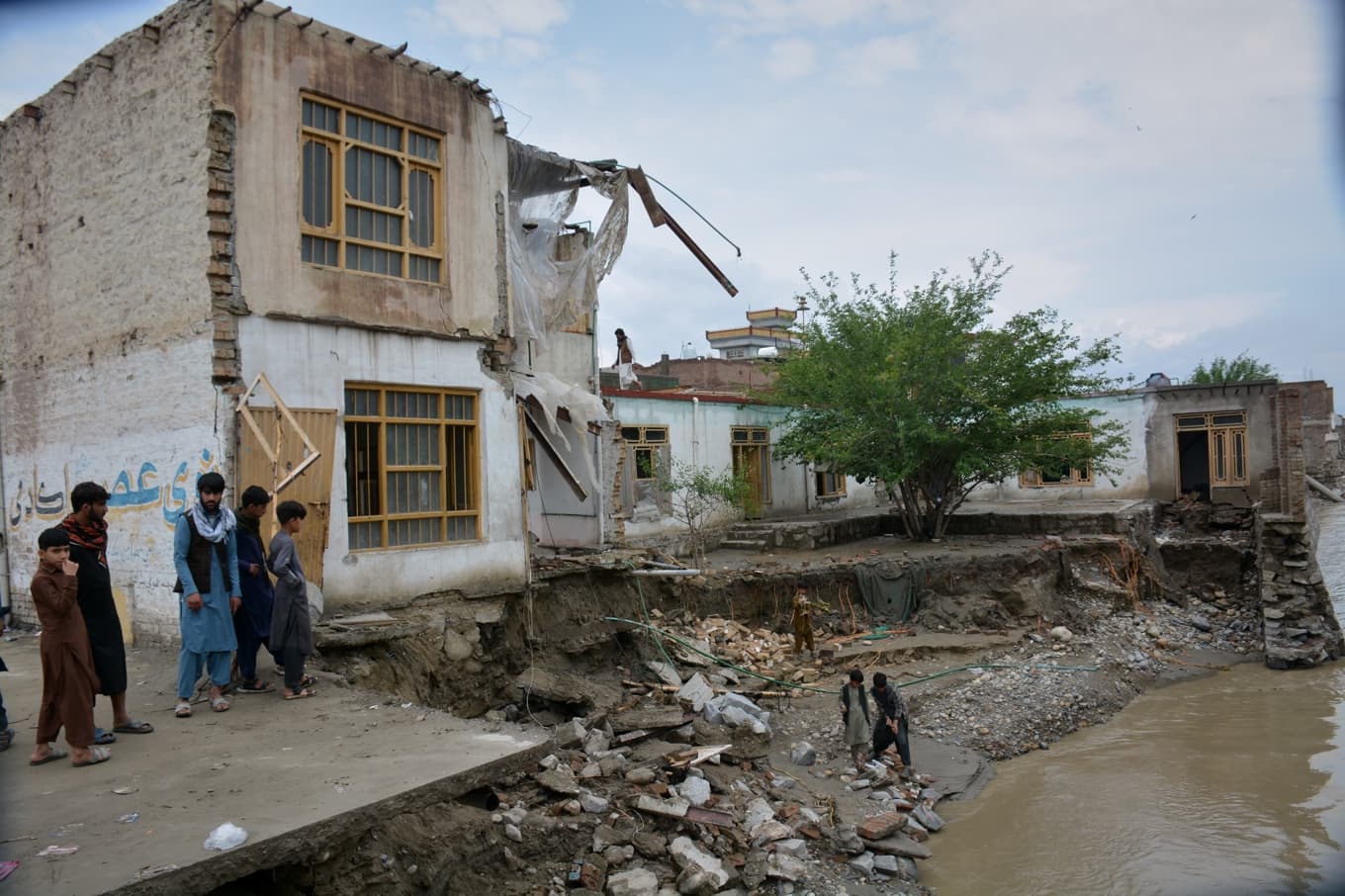 Invånare i Jalalabad, Afghanistan, tittar på ett hus som rasat och delvis sköljts bort. Bilden togs i lördags. Foto: Wahidullah Kakar/AP/TT