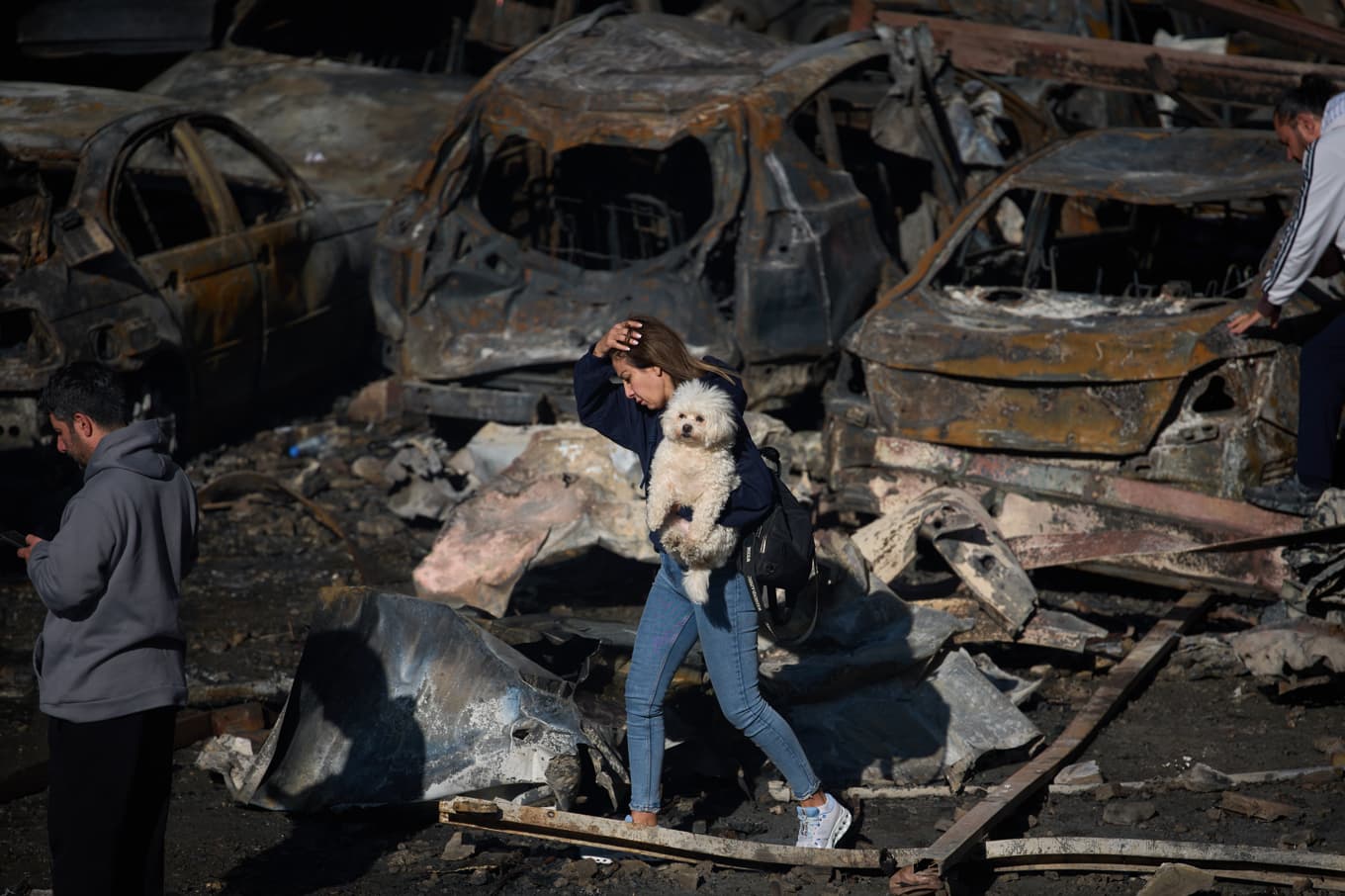 En kvinna går förbi utbrända bilar i Beirut med en hund. Bild tagen på torsdagen. Foto: Emilio Morenatti/AP/TT