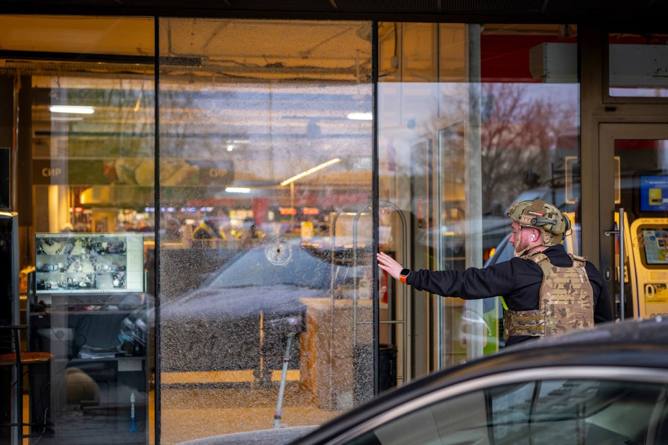 En polis vid den matvarubutik i Kiev där en man tog gisslan efter att ha skjutit ihjäl flera personer på lördagen. Foto: Dan Bashakov/AP/TT