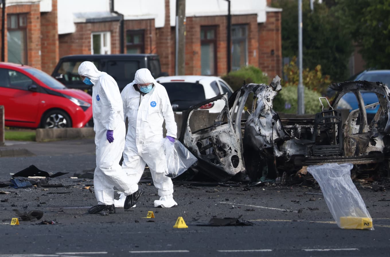 Rättsmedicinska utredare undersöker platsen för en bilbomb som exploderat utanför polisstationen i Dunmurry i södra Belfast. Foto: Peter Morrison/AP/TT