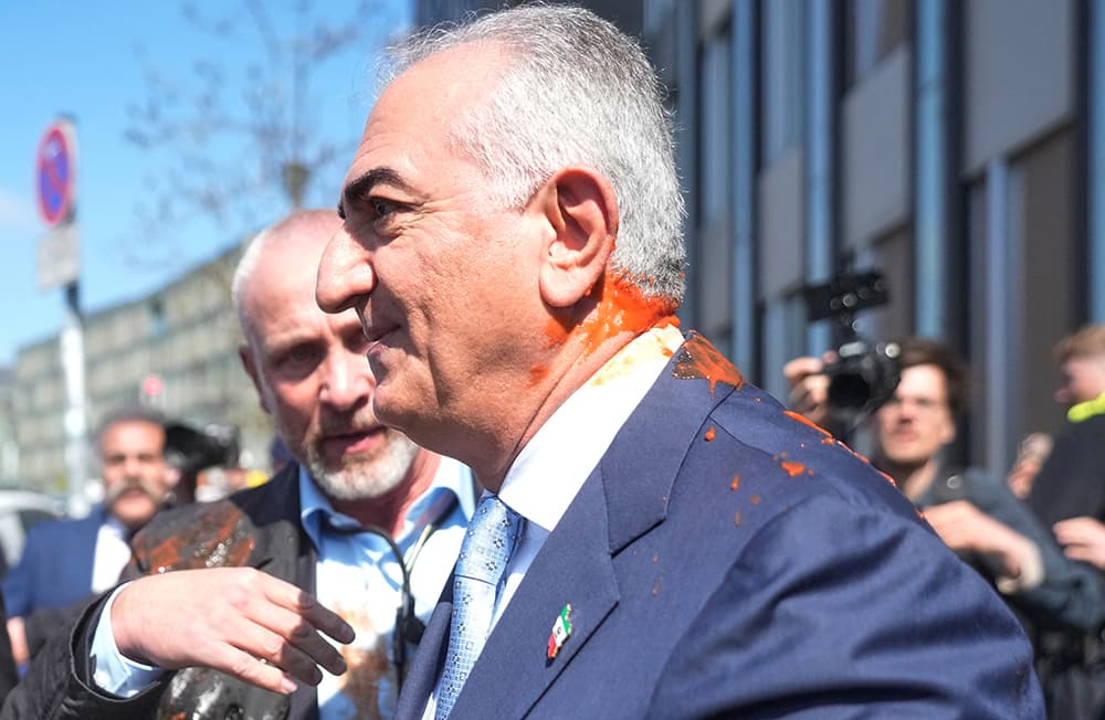 Reza Pahlavi attackerades med en röd vätska, vari den består är oklart. Foto: Markus Schreiber/AP/TT