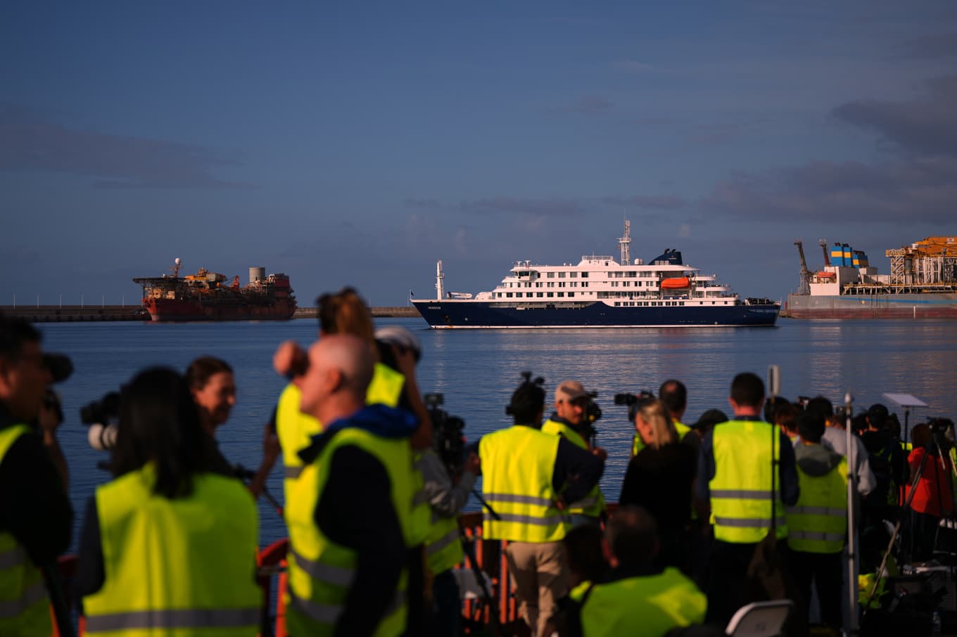 Medier och räddningspersonal i Granadilla, med fartyget i fonden. Foto: Manu Fernandez/AP/TT