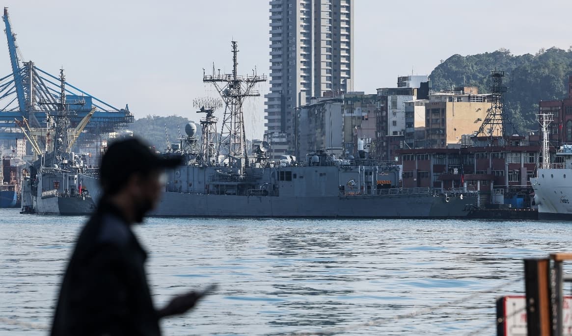 En man står framför taiwanesiska örlogsfartyg som ligger förankrade i hamnen i Keelung den 11 december 2024. Foto: I-HWA CHENG/ Getty Images