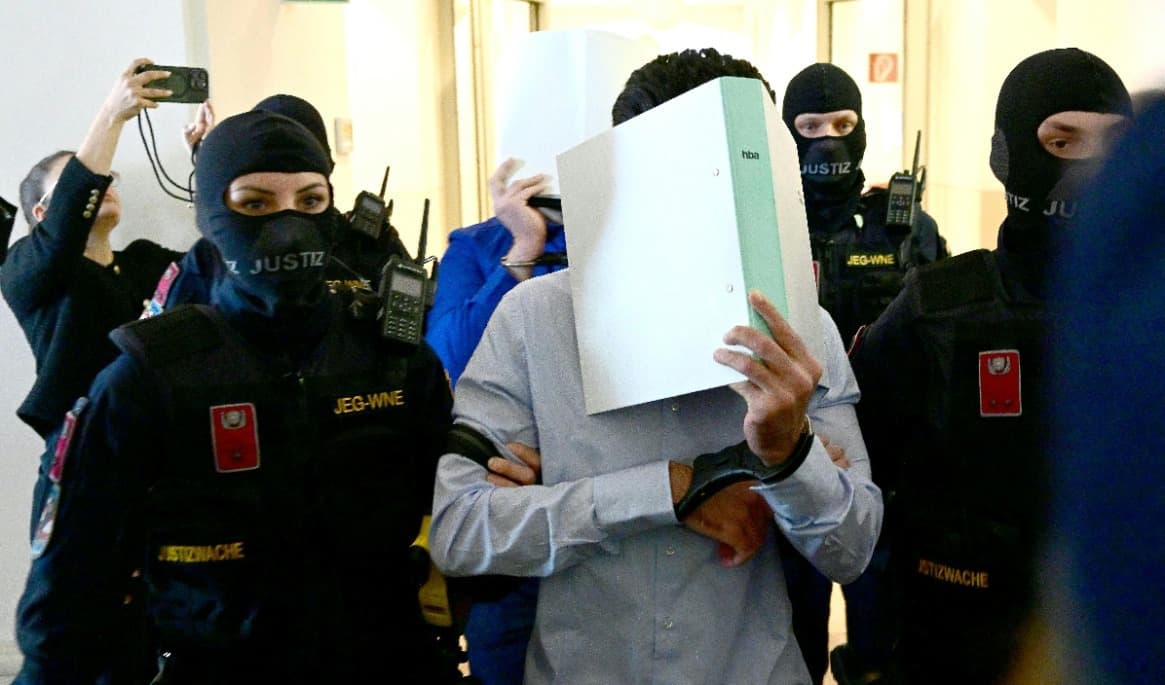 Två åtalade i handbojor eskorteras in i rättssalen av vakter när rättegången inleds vid domstolen i Wiener Neustadt i Österrike den 28 april. Foto: Roland Schlager/APA/AFP via Getty Images