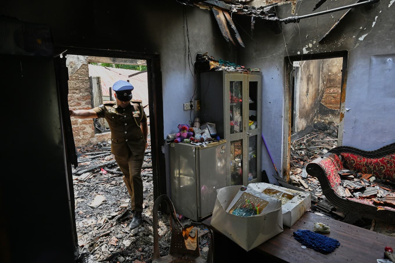 En polis inspekterar det utbrända boendet i Anguruwatota, Sri Lanka. Foto: AP/TT