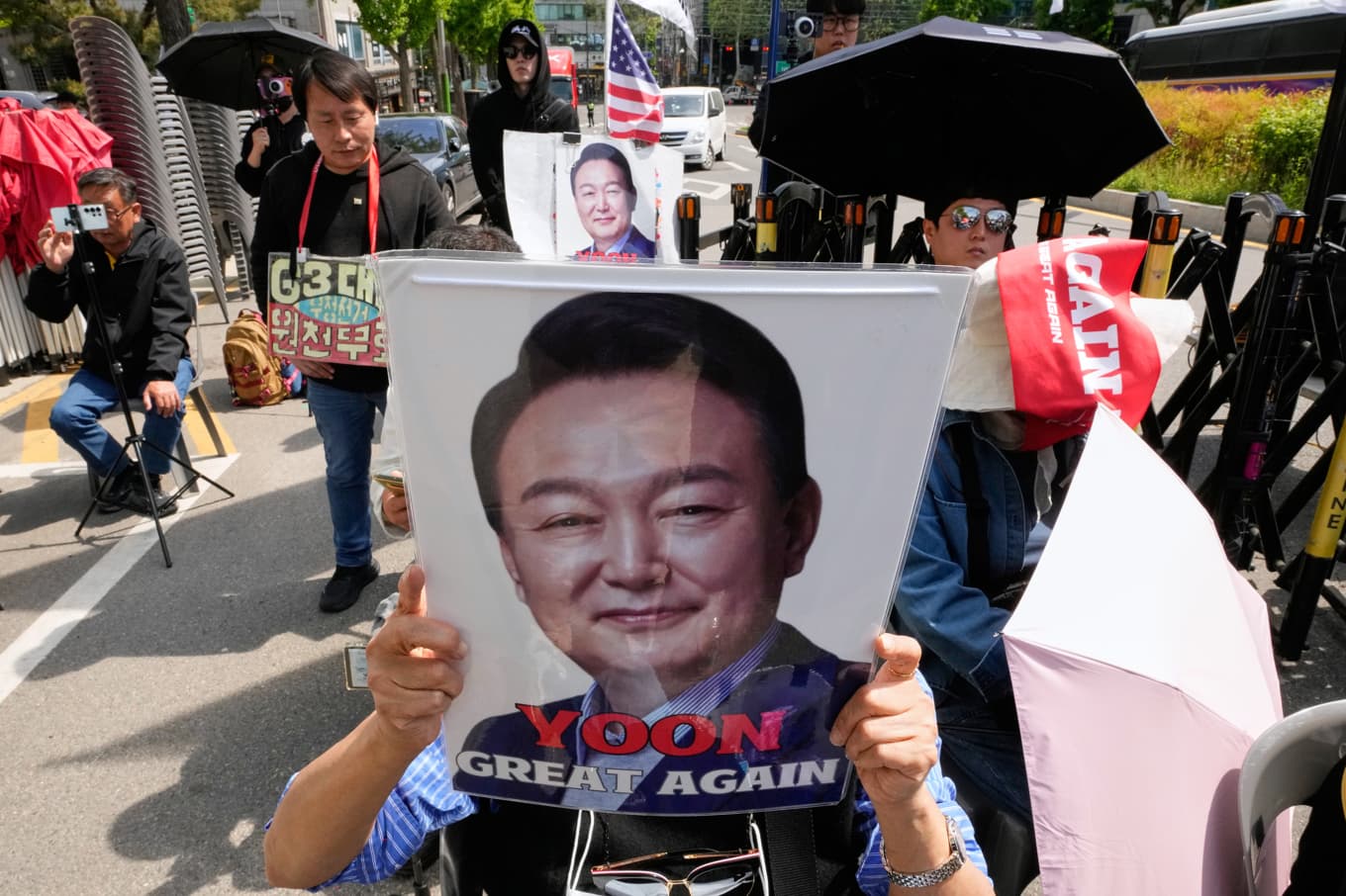 En anhängare av Yoon Suk-Yeol håller upp expresidentens porträtt utanför en domstol. Bild från april i år. Foto: Ahn Young-joon/AP/TT
