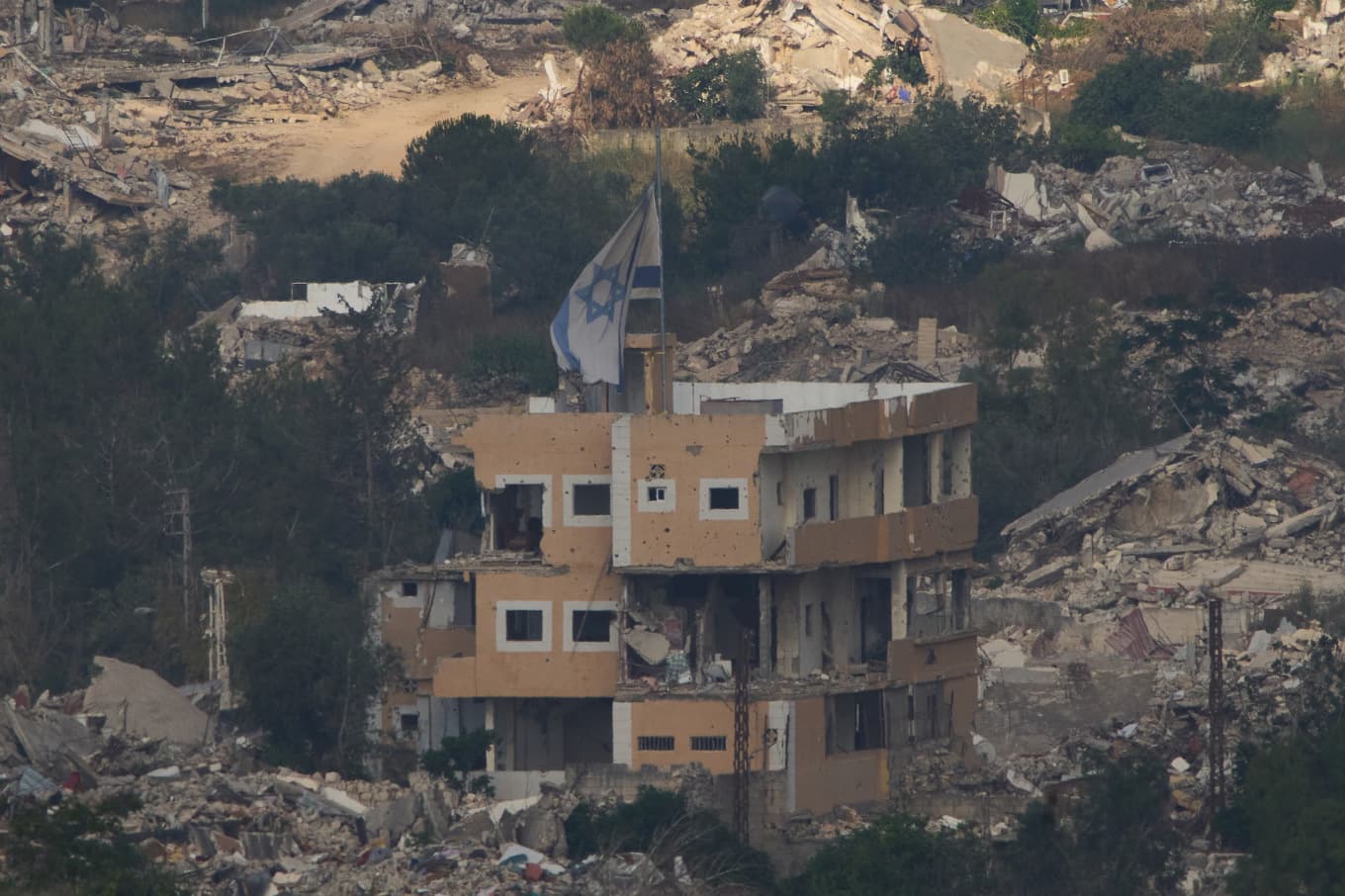 Ett förstört hus med israelisk flagga i södra Libanon syns från gränsen mellan Israel och Libanon. Foto: Ariel Schalit/AP/TT