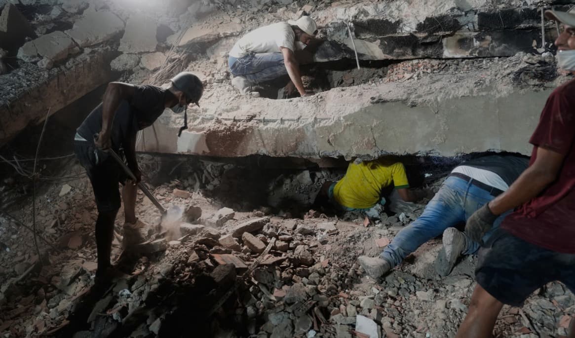 En familj söker efter anhöriga i rasmassorna av en kollapsad byggnad i staden La Guaira, Venezuela. Bild från torsdagen. Foto: Ariana Cubillos/AP/TT