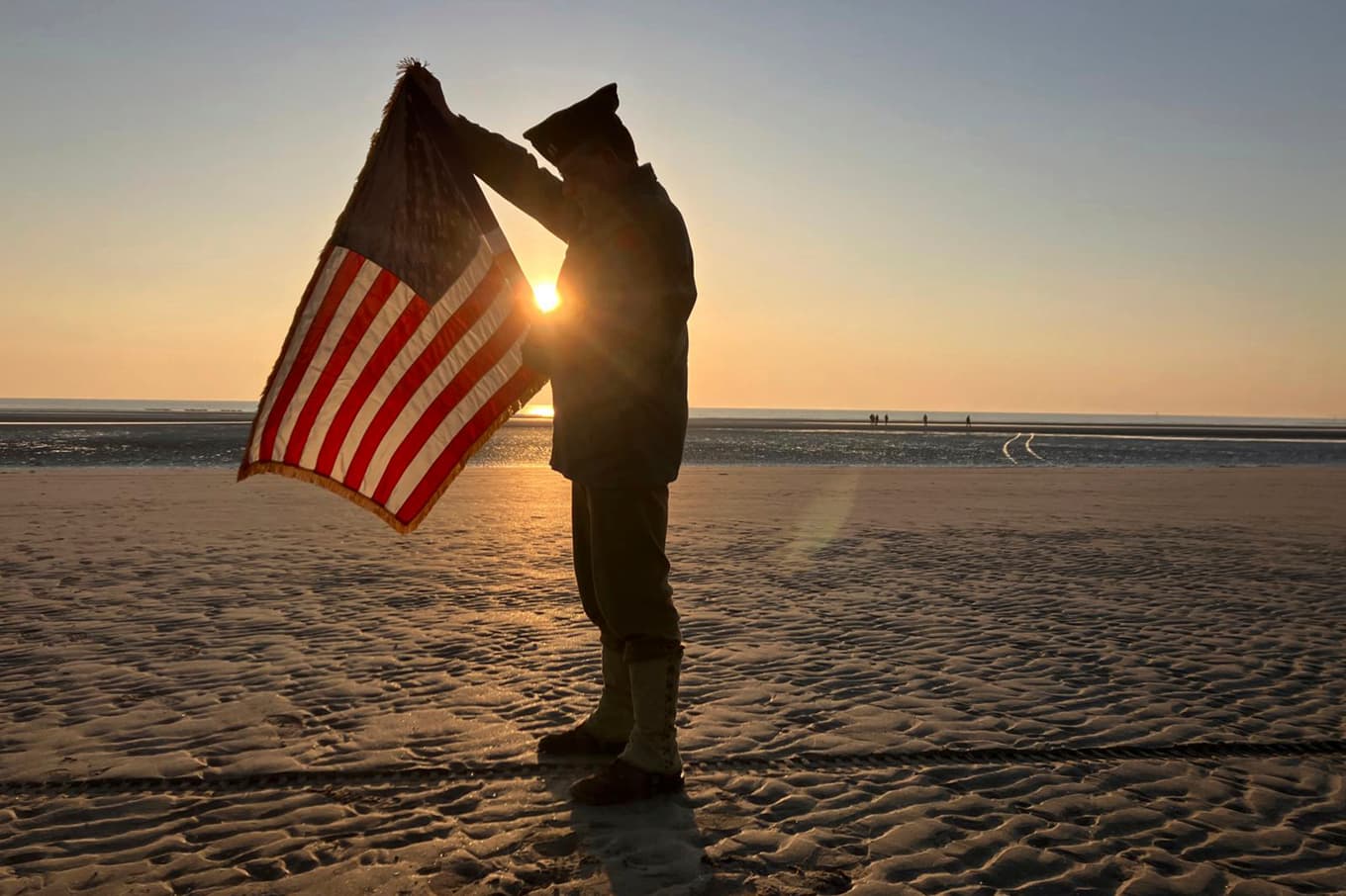 En fransk soldat med den amerikanska flaggan på Utah Beach vid 80-årsminnet av invasionen. Foto: John Leicester/AP/TT