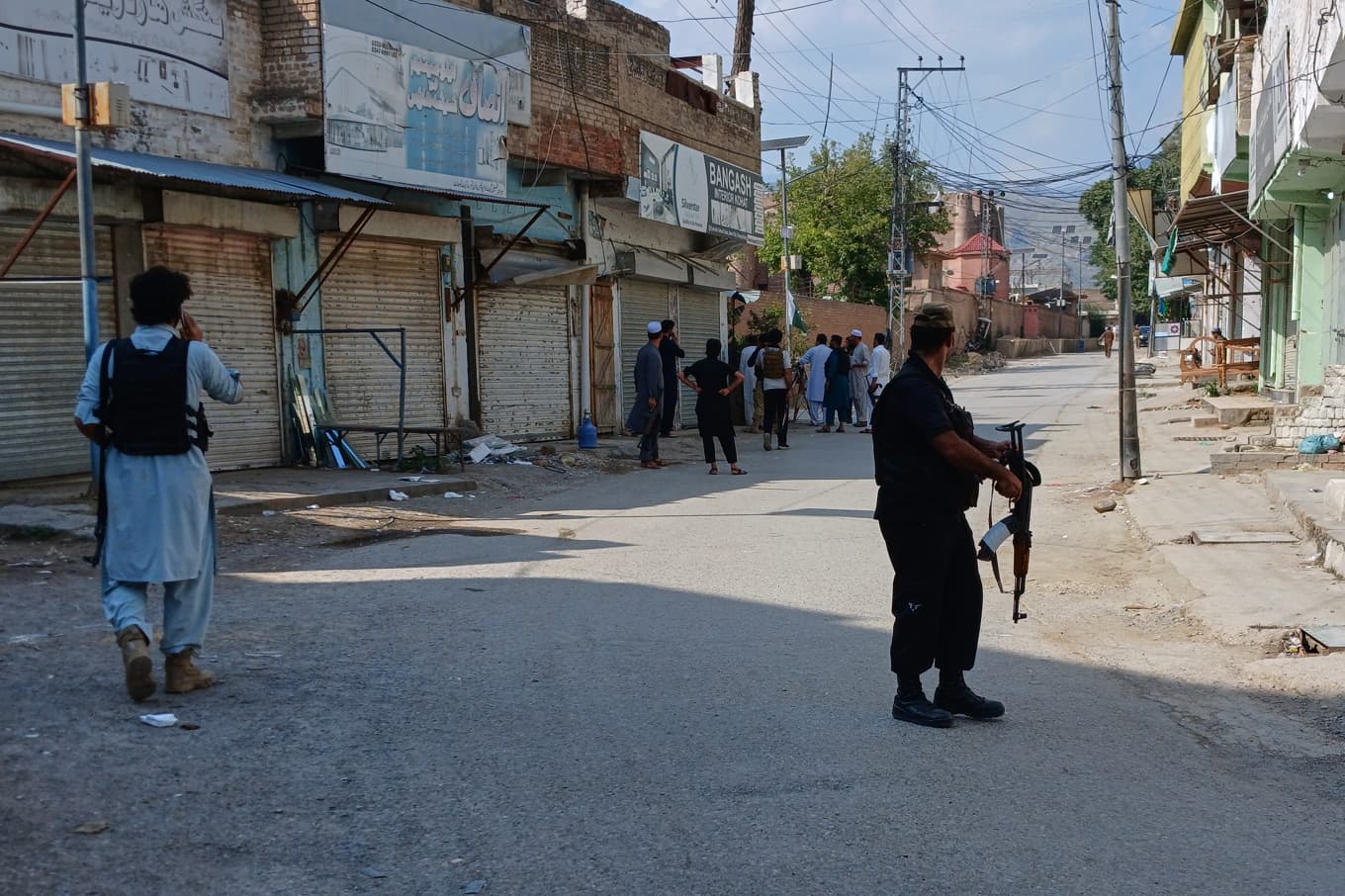 Beväpnade poliser håller koll på en väg i närheten av platsen där en bil lastad med sprängmedel exploderade. Bilden togs med en mobilkamera på fredagseftermiddagen. Foto: B.S. Gillani/AP/TT