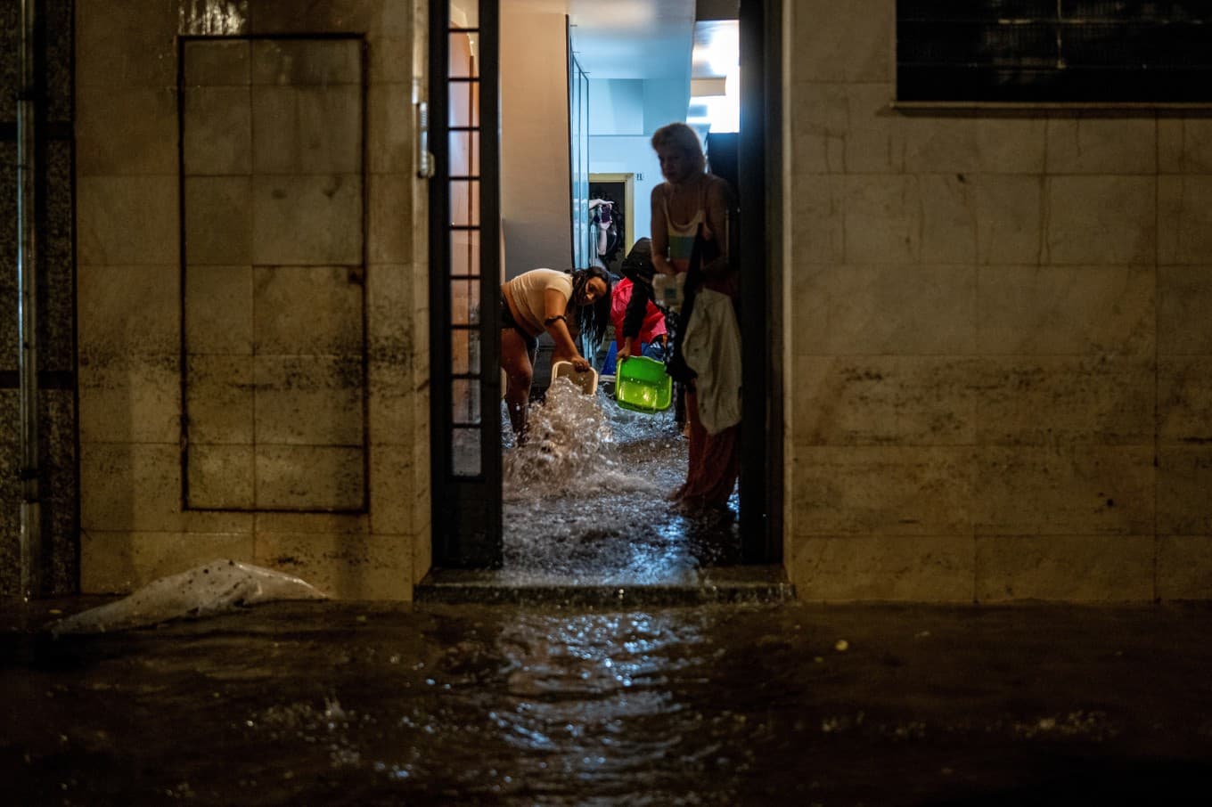Två kvinnor skyfflar ut vatten från sina översvämmade bostäder i L'Hospitalet de Llobregat i utkanten av Barcelona. Foto: Lorena Sopena/AP/TT