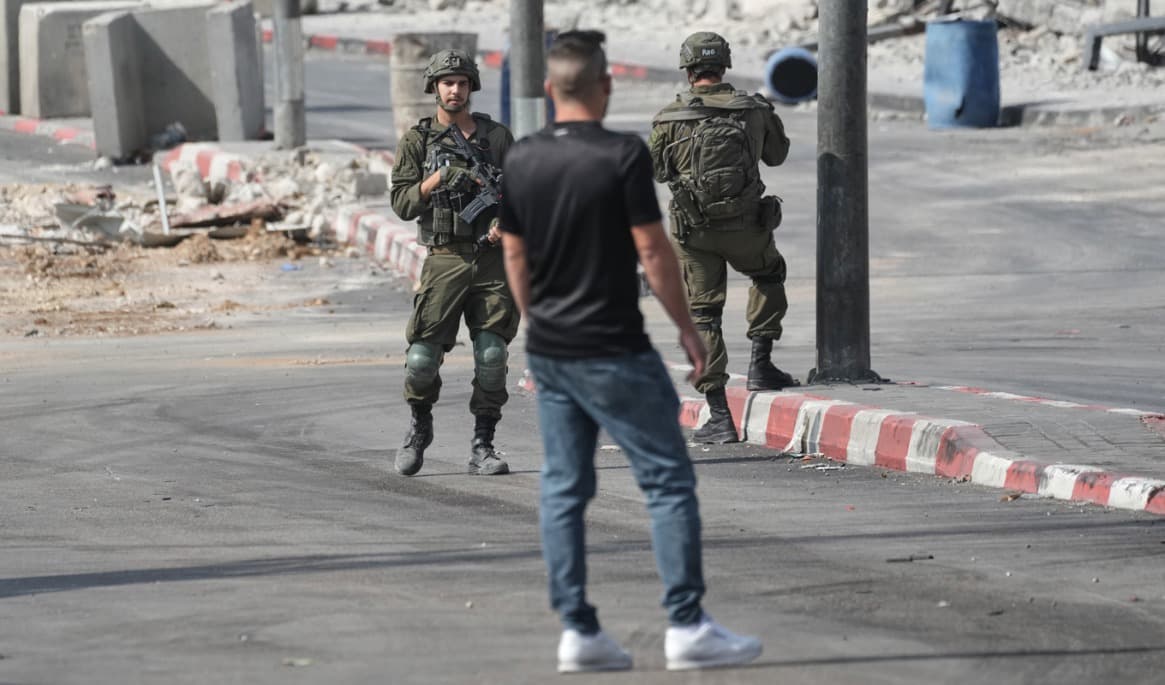 En palestinsk man framför två israeliska soldater i Hebron på lördagen. Foto: Mahmoud Illean/AP/TT