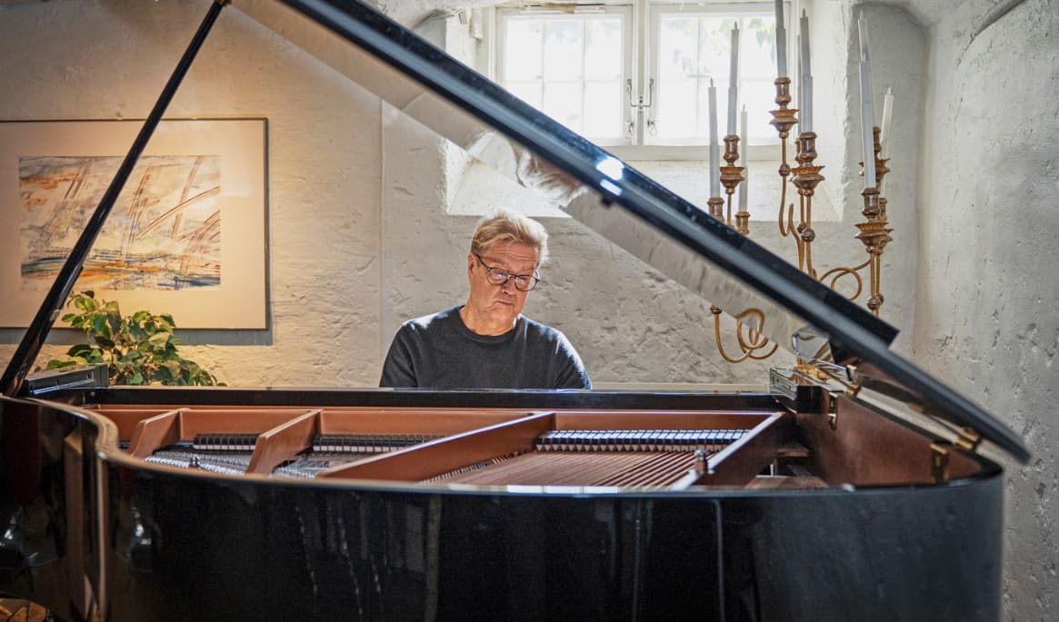 Matti Hirvonen vid flygeln i sin studio i Lärkstan i Stockholm. Här förbereds konserter och besök av kunskapstörstande musiker och sångare. Foto: Sofia Drevemo