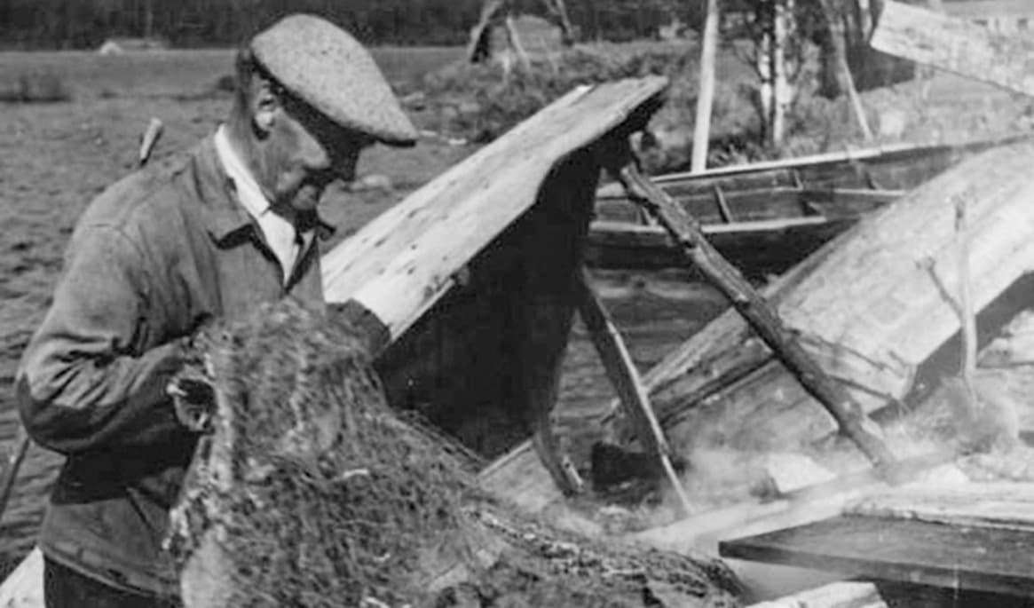 Oskar Byström i Juktå, 77 år, arbetar med tålning av fiskenäten vid stranden av Storjuktan. Juktå, Sorsele, Lappland år 1955–1956. Foto: Ernst Westerlund/Isof