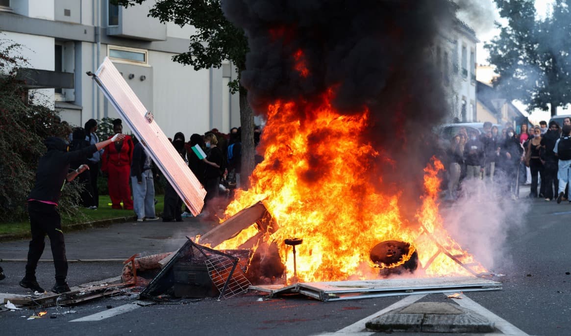 En person kastar föremål in i en eld medan protesterande elever genomför en blockadaktion i Brest i västra Frankrike den 2 oktober. Sedan slutet av september har elever protesterat mot bland annat missnöje med scheman, storleken på klasser och lärarbrist. Foto: Fred Tanneau/AFP via Getty Images
