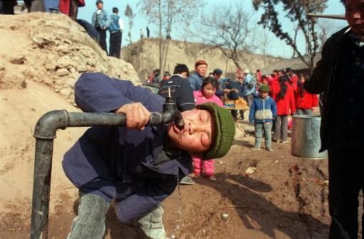 En pojke släcker törsten i en by i Kina. (Foto: Joe Zhouqing/AFP)