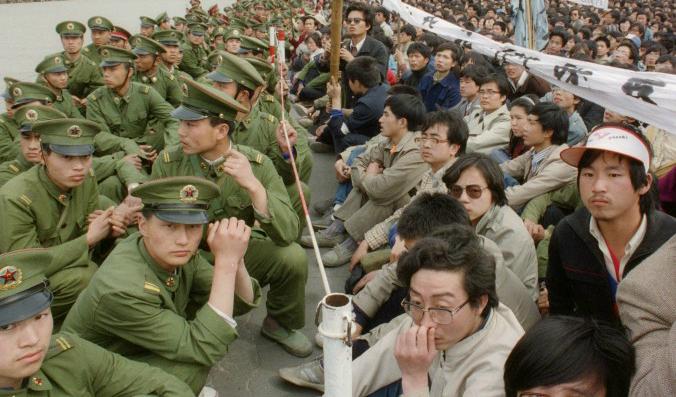 Några hundra av de 200 000 prodemokratiska studenterna sitter ansikte mot ansikte med soldarer på Himmelska fridens torg, 22 april 1989. Foto: Catherine Henriette/AFP/Getty Images