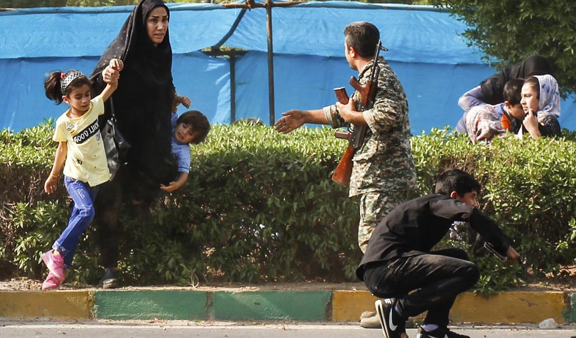En kvinna och hennes barn tar skydd medan en soldat försöker hjälpa dem under attentatet i Ahvaz, Iran. Foto: Fatemeh Rahimavian/AP/TT