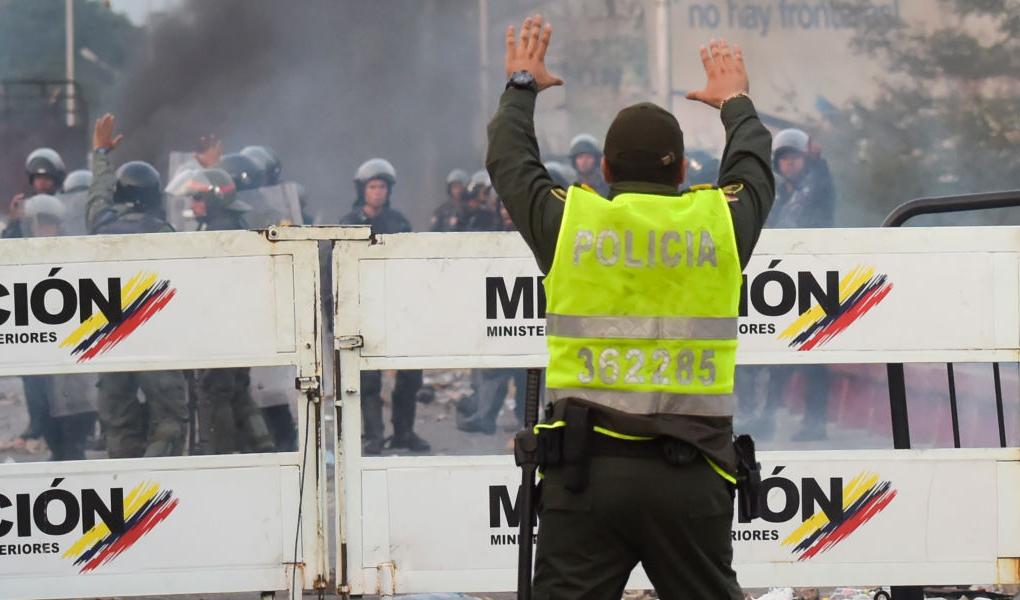 En Colombiansk polis gestikulerar till Venezuelanska säkerhetsstyrkor på Francisco de Paula Santander International Bridge vid gränsen mellan de två länderna, den 25 februari 2019. Foto: Raul Arboleda/AFP/Getty Images