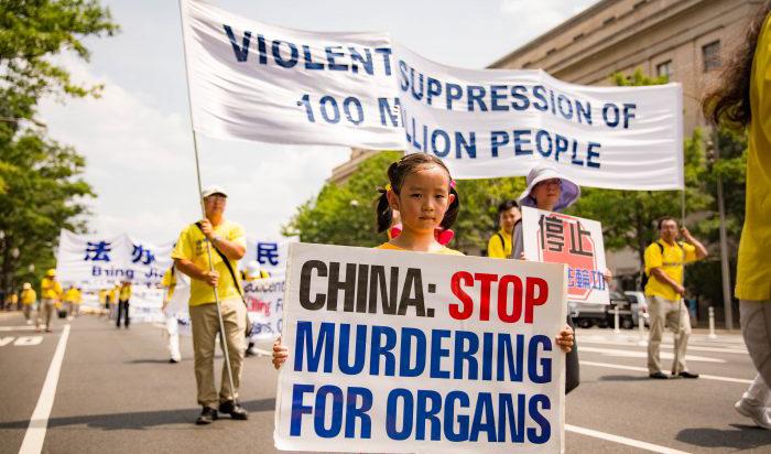 En ung Falun Gong-utövare håller en skylt som ber Kina att sluta döda samvetsfångar för deras organ. Paraden gick genom Washington 20 juli 2017. Foto: Benjamin Chasteen/The Epoch Times