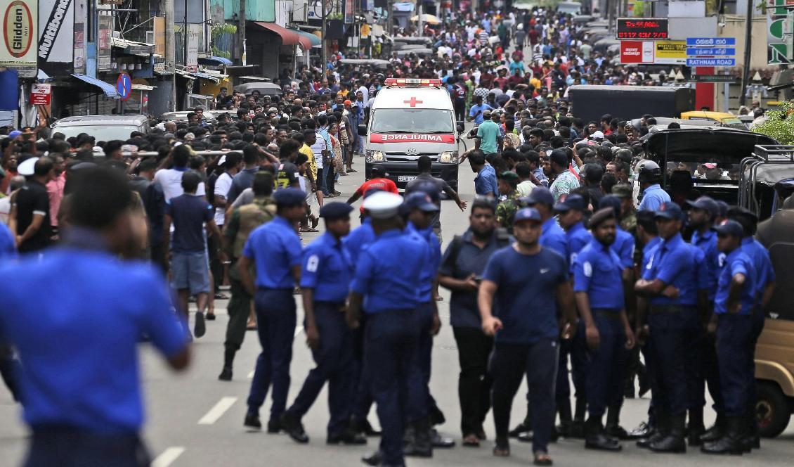 Poliser i Sri Lanka försöker ge fri väg åt en ambulans. Foto: Eranga Jayawardena/AP/TT