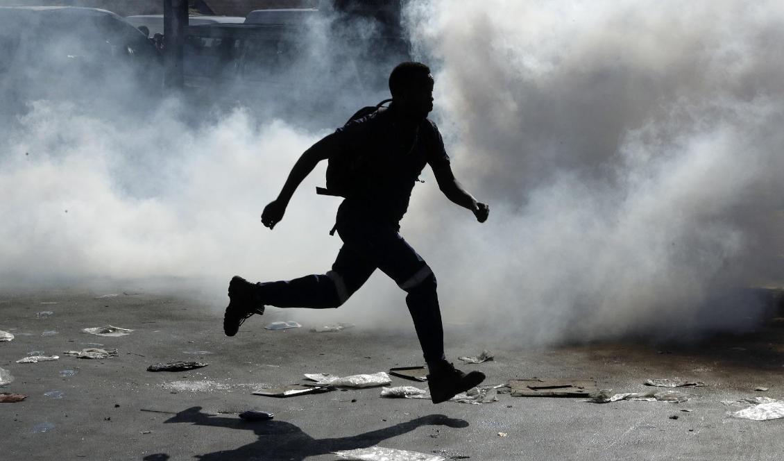 En man springer bort från tårgas i samband med att en butik plundrats i Germiston, öster om Johannesburg, i förra veckan. Foto: Themba Hadebe/AP/TT
