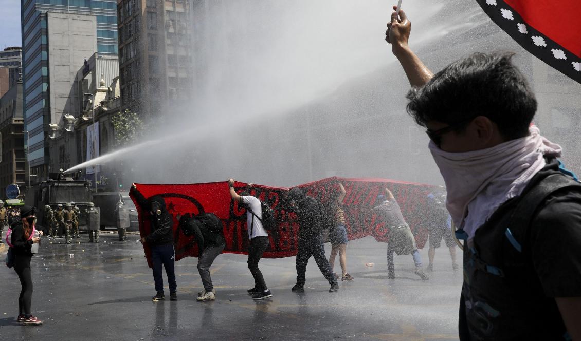 Även om onsdagens protester var lugnare än tidigare sattes vattenkanoner in mot demonstranter i Chiles huvudstad Santiago. Foto: Rodrigo Abd/AP/TT