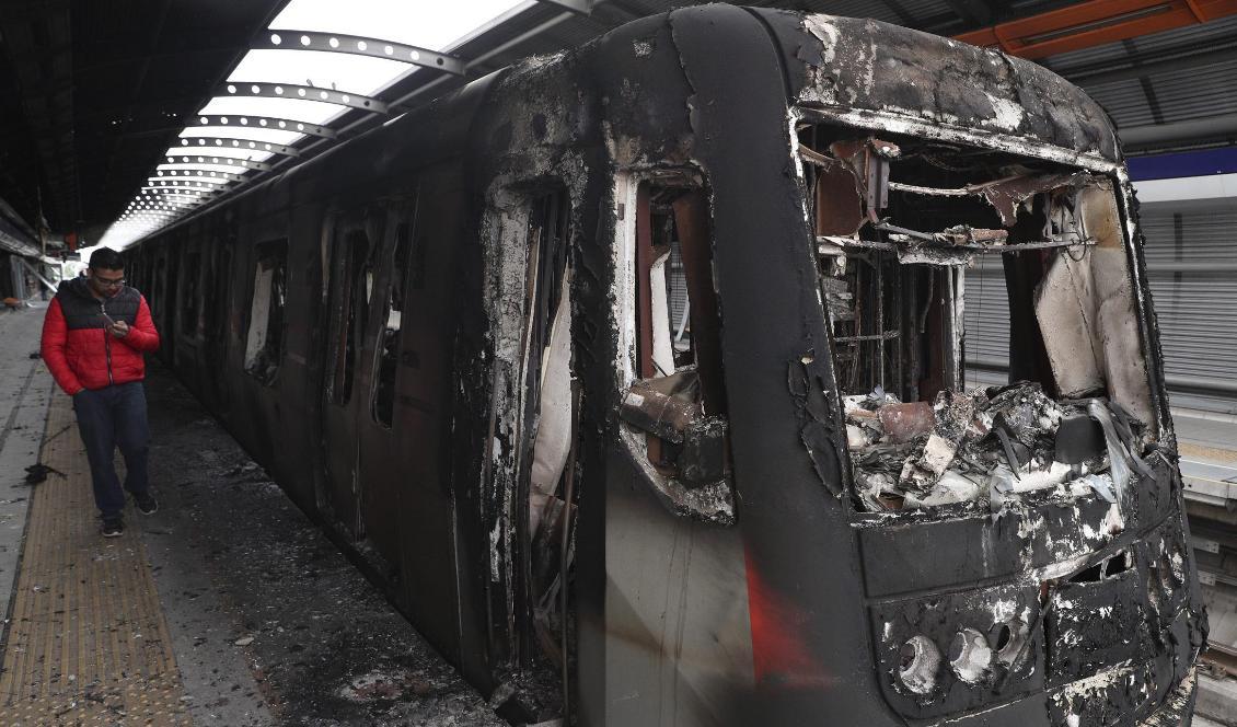 Flera bränder har anlagts i samband med protesterna i Santiago. Här är en tunnelbanevagn som bränts. Foto: Esteban Felix/AP/TT