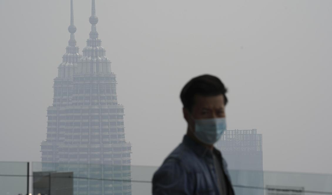 En turist i Kuala Lumpur med munskydd som skydd mot röken som väller in från skogsbränderna i grannlandet. Foto: Vincent Thian/AP/TT