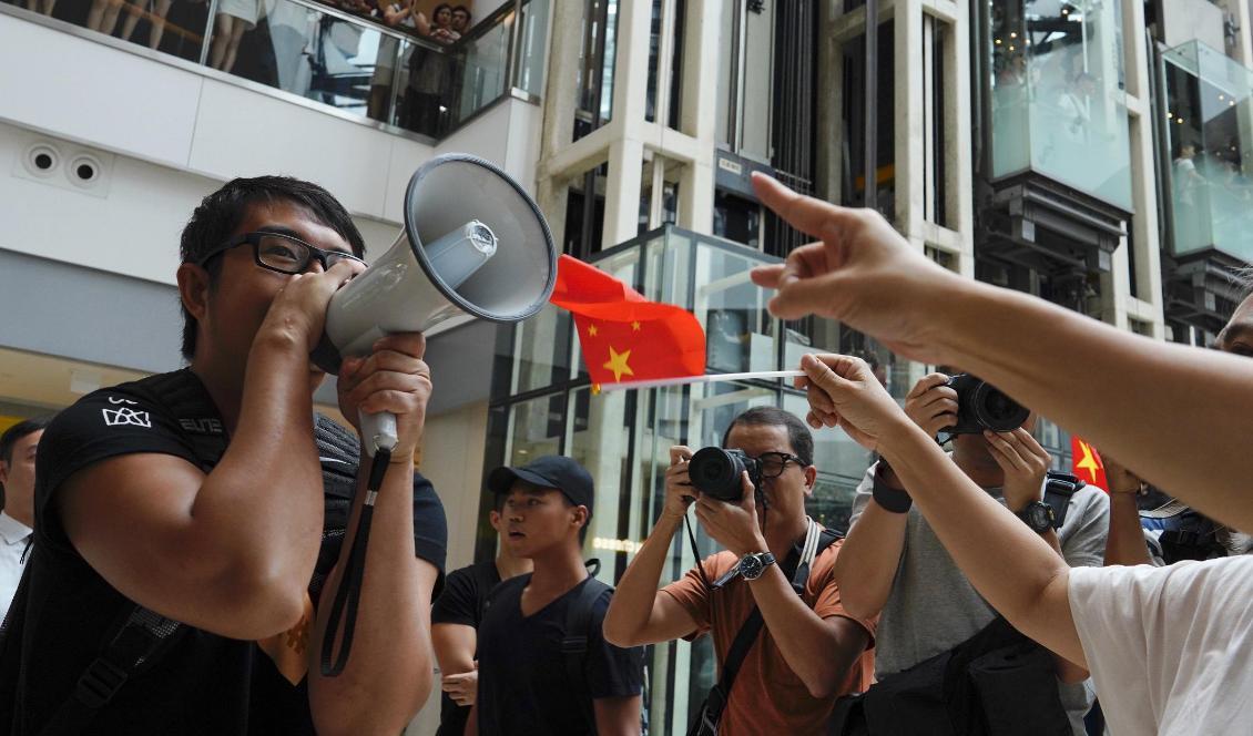 En demonstrant från proteströrelsen försöker göra sin röst hörd framför prokinesiska demonstranter i ett köpcentrum i Hongkong. Bilden togs fredagen den 13 september. Foto: Vincent Yu/AP/TT