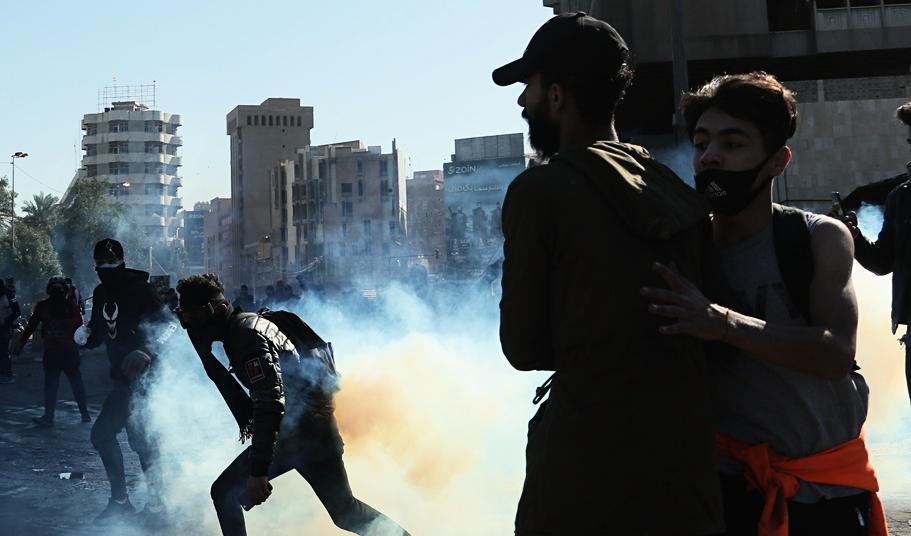 
Regeringskritiska demonstranter flyr undan säkerhetsstyrkornas tårgas vid protester i Bagdad på söndagen. Foto: Hadi Mizban/AP/TT                                                
