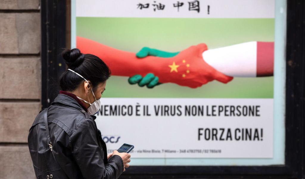

En kvinna går förbi en anslag med texten "Viruset är fienden, inte folket. Heja Kina!" i Milano den 25 februari 2020. Foto: Emanuele Cremaschi/Getty Images                                                                                            