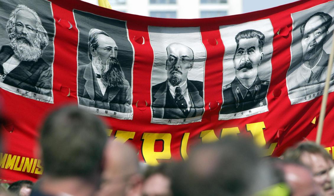 Demonstranter håller upp en banderoll med bilder på de stora kommunisterna, från vänster, Karl Marx, Friedrich Engels, Lenin, Stalin och Mao Zedong under en förstamajparad på Berlin's Alexanderplatz, den 1 maj 2005 i Berlin, Tyskland.