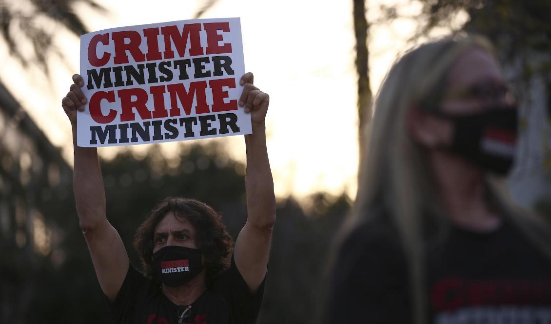 Motståndare till Netanyahu med plakat och munskydd märkta "crime minister". Bilden är från april. Foto: Oded Balilty/AP/TT