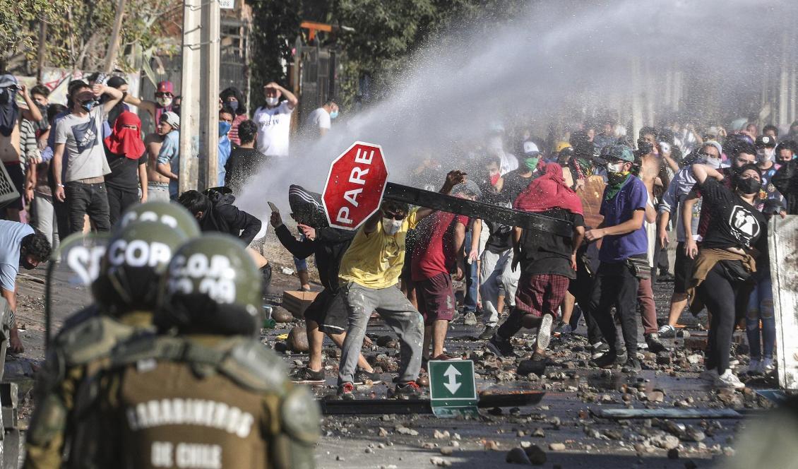 Demonstranter – en del med munskydd – drabbade samman med polis under måndagen. Nu har soldater satts in i Santiago. Foto: Esteban Felix/AP/TT