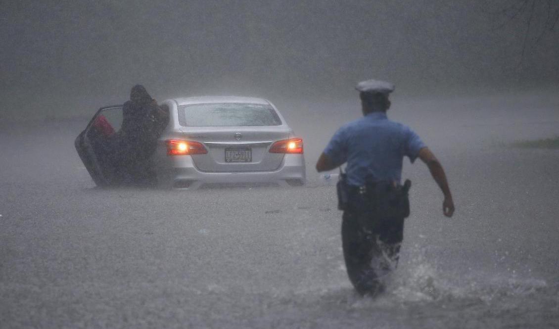 Polis rycker ut för att hjälpa en bilist som fastnat i vattenmassorna i Philadelphia. Foto: Matt Slocum/AP/TT