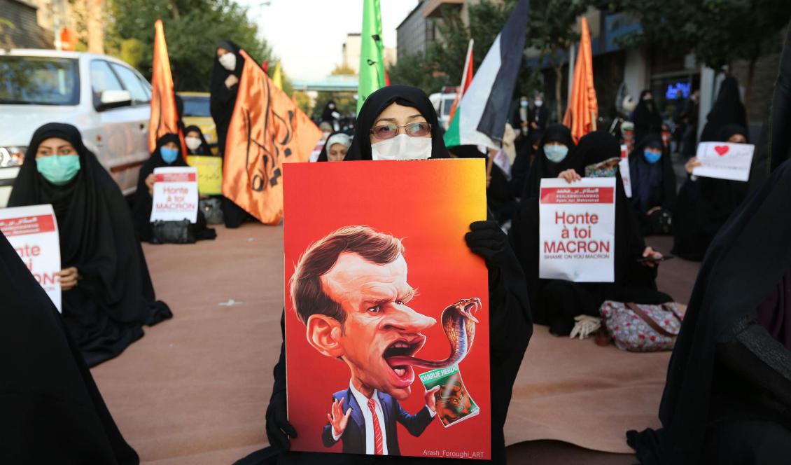 En iransk kvinna håller en karikatyr av den franske presidenten Emmanuel Macron, med en orms tunga, under en protest utanför franska ambassaden i Teheran, den 28 oktober 2020. Foto: Atta Kenare/AFP via Getty Images
