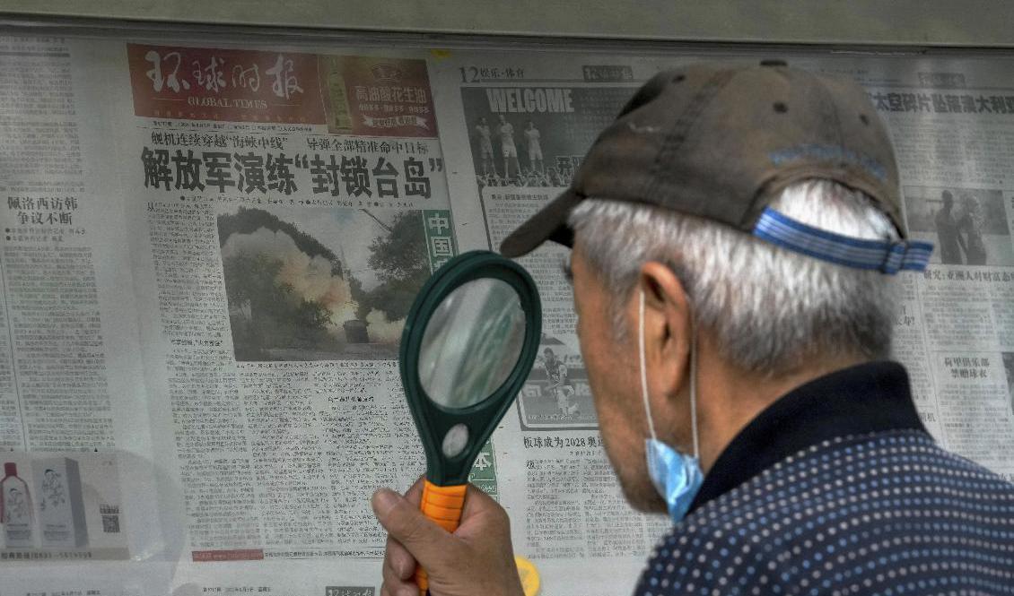 

En man använder förstoringsglas för att läsa om Kinas militärövning runt Taiwan under söndagen. Foto: Andy Wong/AP/TT                                                                                        