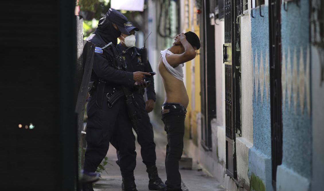 Poliser kroppsvisiterar en man under en sökinsats efter gängmedlemmar i Soyapango utanför San Salvador den 16 augusti. Foto: Salvador Melendez/AP/TT