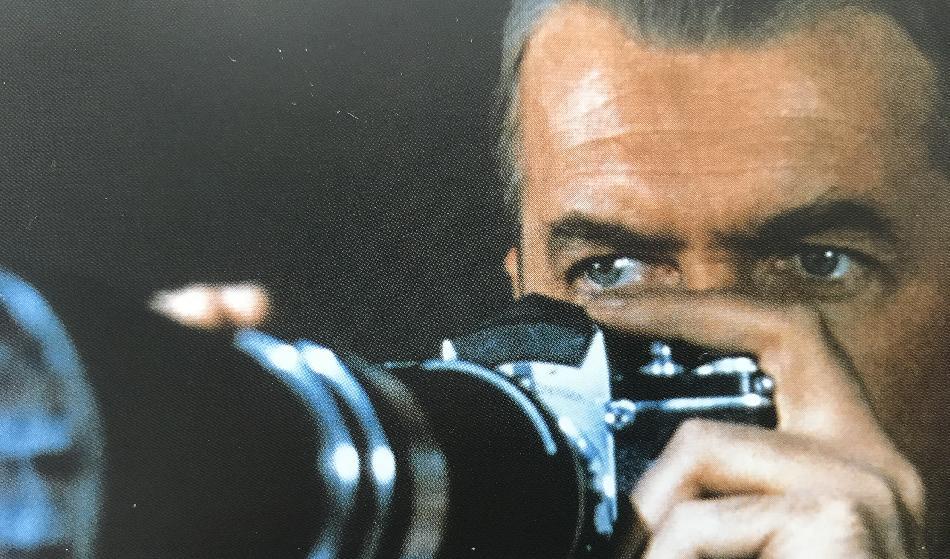 Jeff (James Stewart) spionerar på sina grannar från sitt dunkla vardagsrum i klassikern Fönstret åt gården från 1954. Filmbild - Ida Fältander